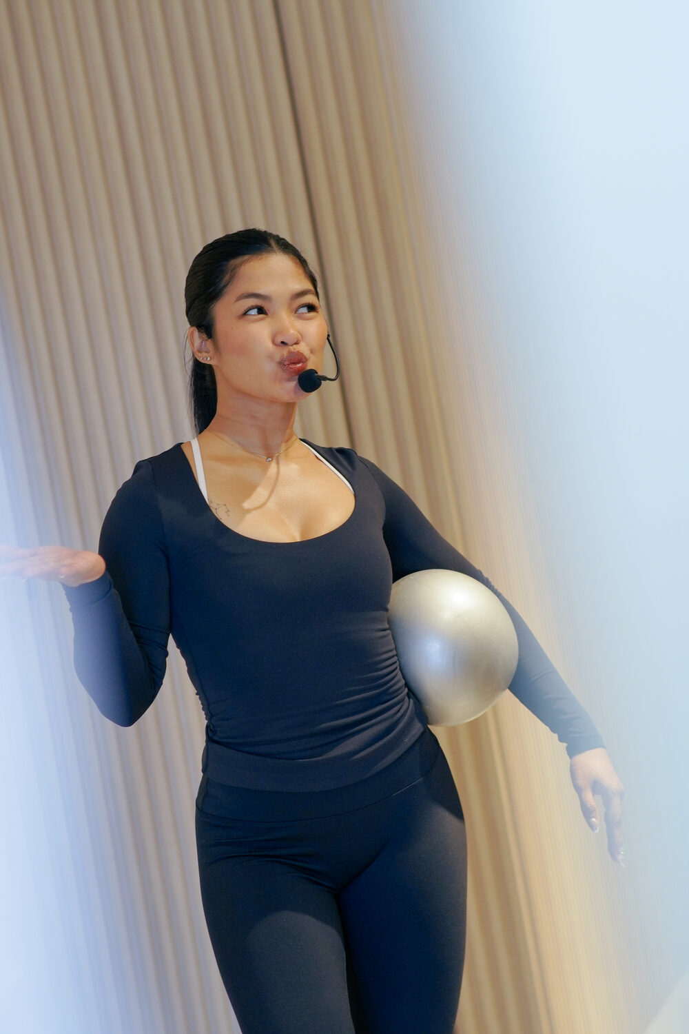 Keisha Sta Maria coaching in the studio, headset mic, holding a stability ball
